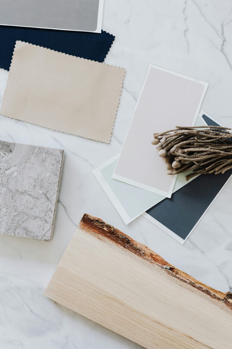 Flat lay of material samples for interior design including wood, marble, and textiles.